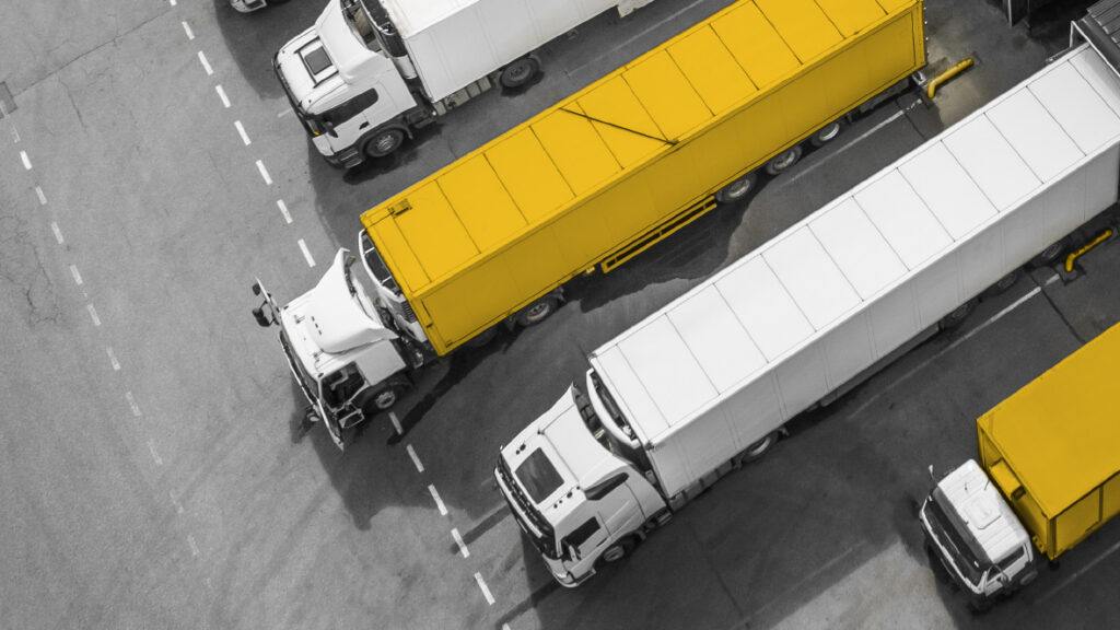 Dalla congestione all’efficienza: come il Time Slot Management ottimizza i piazzali 2 Camion bianchi e gialli in piazzale logistico — pianificazione dei flussi e riduzione delle attese grazie al Time Slot Management Transporeon.