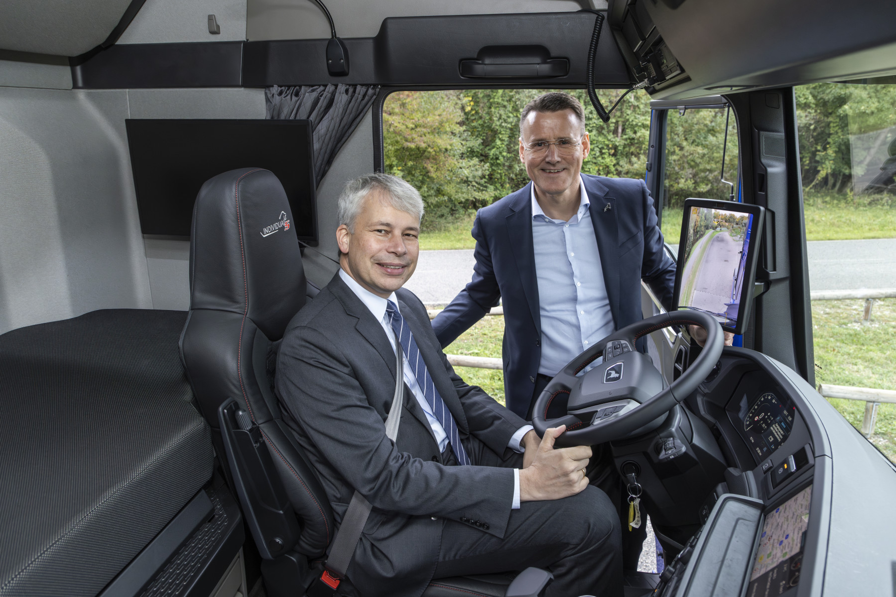 Il ministro federale tedesco dei Trasporti, Steffen Bilger (a sinistra), al volante del nuovo camion elettrico MAN eTruck. Alexander Vlaskamp (a destra), presidente del Consiglio di amministrazione di MAN, gli ha illustrato le tecnologie del veicolo elettrico.