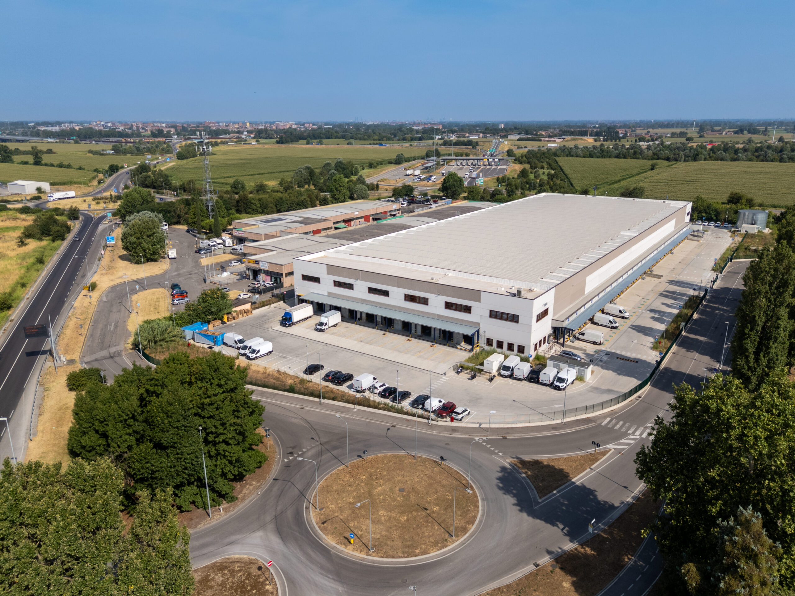 Vista aerea del polo logistico Logicor a Sordio, in provincia di Lodi, con aree di carico, parcheggi e collegamenti alla rete stradale